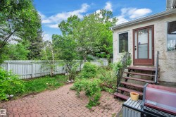 Exterior patio area featuring red brick pavers and a wooden staircase providing access to the property - 