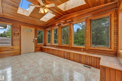 Sunroom featuring extensive wood paneling and trim throughout, multiple skylights, a ceiling fan, and large windows - 10819 54 Avenue, Edmonton, AB 