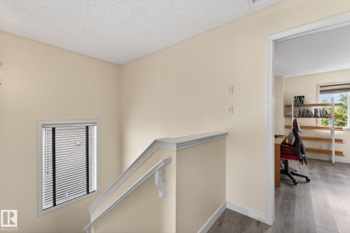 Stairway landing featuring a white painted handrail and balustrade, a window with horizontal blinds, and neutral-toned walls - 21244 90 Avenue, Edmonton, AB 