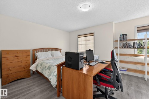 Room featuring wood-finish flooring, two windows with blinds, a ceiling-mounted light fixture, a built-in shelving unit, and neutral wall paint - 21244 90 Avenue, Edmonton, AB 
