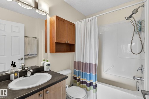 Full bathroom featuring a white porcelain tub/shower combination, chrome fixtures, and a vanity with a dark countertop and oval undermount sink - 21244 90 Avenue, Edmonton, AB 