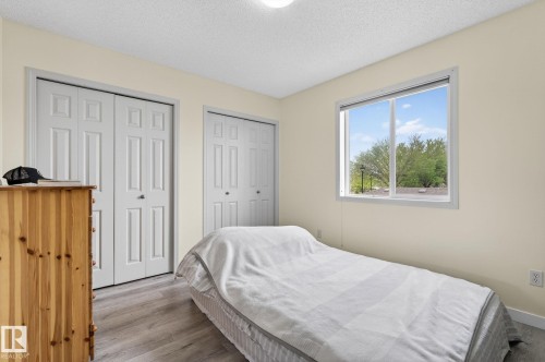 Room featuring light wood-finish flooring, a large window, a ceiling-mounted light fixture, and two sets of bi-fold closet doors - 21244 90 Avenue, Edmonton, AB 
