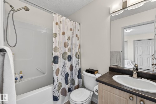 Bathroom featuring a white bathtub with a shower attachment, a toilet, and a vanity with an integrated sink - 21244 90 Avenue, Edmonton, AB 