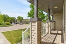 Covered front porch with wood-finish decking and white railing - 21244 90 Avenue, Edmonton, AB 