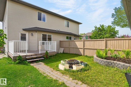 Rear exterior featuring beige siding, a wood-finish deck with white railings, and a fenced backyard - 21244 90 Avenue, Edmonton, AB 