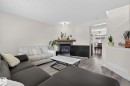 Living room featuring a gas fireplace with a stone surround and wood-finish mantel, wood-finish flooring, and recessed lighting - 21244 90 Avenue, Edmonton, AB 