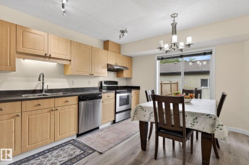 Kitchen and dining area featuring wood-finish cabinetry, dark countertops, and stainless steel appliances - 21244 90 Avenue, Edmonton, AB 