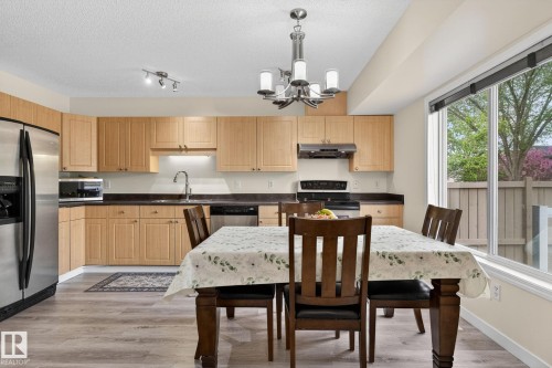 Kitchen featuring wood-finish cabinetry, stainless steel appliances, dark countertops, and wood-finish flooring - 21244 90 Avenue, Edmonton, AB 
