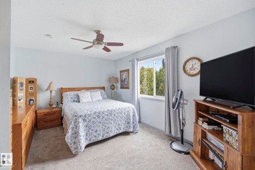 Bedroom featuring neutral carpeting, a ceiling fan, a window with exterior views, and light-toned walls - 3231 28A Avenue, Edmonton, AB 