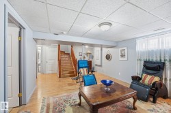 Open-concept room featuring wood-finish flooring, light grey wall paint, and a white acoustical tile ceiling - 
