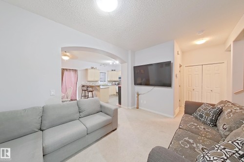 Open-concept living area with light-toned carpet flooring and neutral wall finishes - 41 5102 30 Avenue, Beaumont, AB 