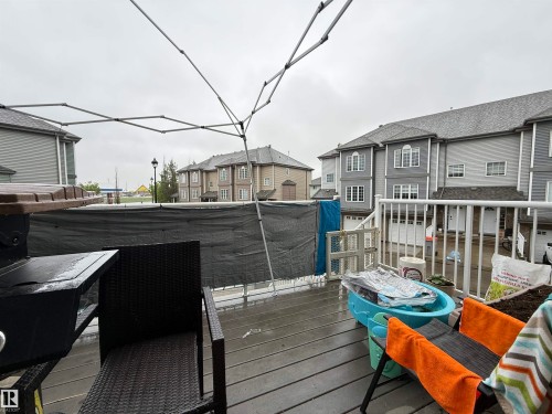 Outdoor deck featuring dark wood-finish flooring, white railings, and a privacy screen - 41 5102 30 Avenue, Beaumont, AB 