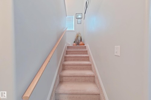 Carpeted staircase featuring a light wood handrail and a window with horizontal blinds - 41 5102 30 Avenue, Beaumont, AB 