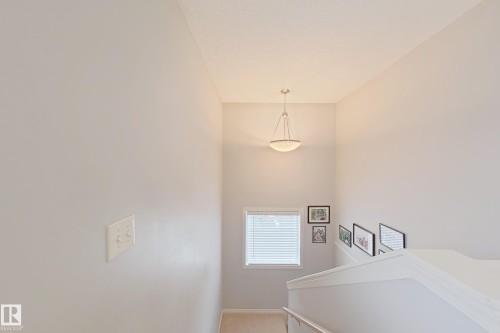 Stairwell featuring light gray walls, a window with horizontal blinds, and a semi-flush mount ceiling light fixture - 41 5102 30 Avenue, Beaumont, AB 