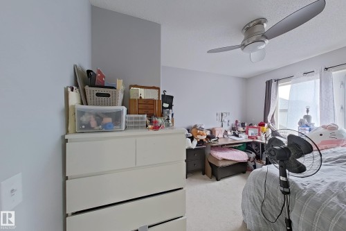 Carpeted room with a ceiling fan featuring integrated lighting, light-toned walls, and a window with a dark curtain rod - 41 5102 30 Avenue, Beaumont, AB 