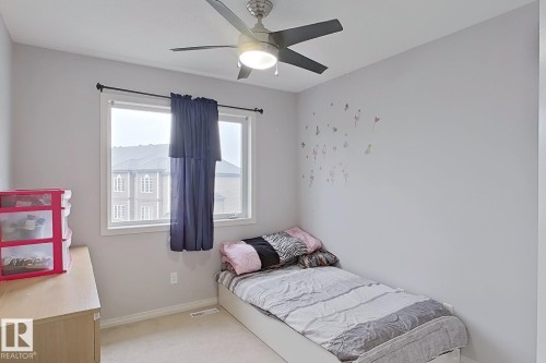Room with light neutral wall paint, a window featuring a dark curtain, a ceiling fan with integrated lighting, and light-colored carpeting - 41 5102 30 Avenue, Beaumont, AB 