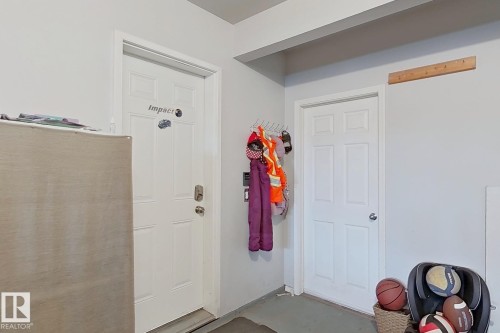 Interior space featuring two white paneled doors, light grey walls, and a grey concrete floor - 41 5102 30 Avenue, Beaumont, AB 