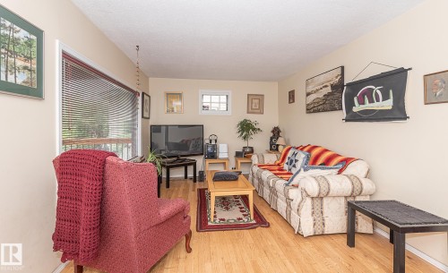 Living area featuring wood-finish flooring, a large window with blinds, and neutral wall paint - 9623 110A Avenue, Edmonton, AB 