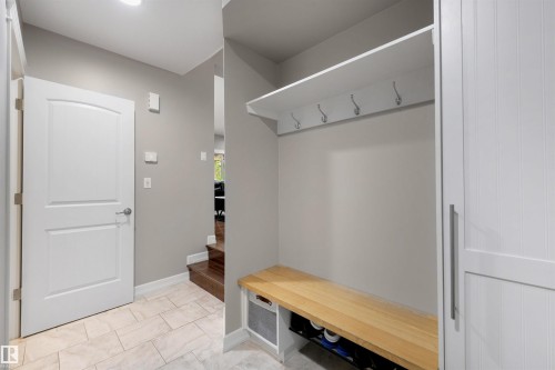 Entryway featuring built-in storage with a natural wood-finish bench, white beadboard cabinetry, and a white shelf with coat hooks - 1507 Wates Place Sw, Edmonton, AB 