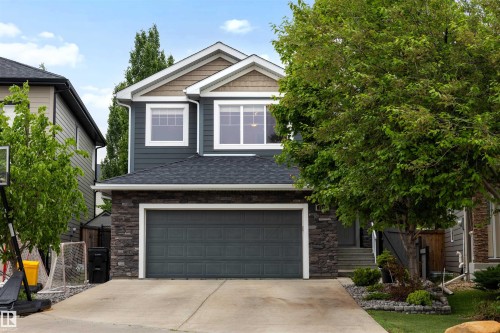 Two-story residence featuring dark siding with stone accents and a prominent two-car garage - 1507 Wates Place Sw, Edmonton, AB 