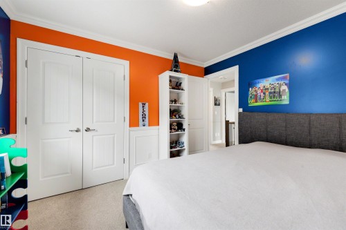 Carpeted room featuring a white ceiling with crown molding, two-panel interior doors, and a built-in shelving unit - 1507 Wates Place Sw, Edmonton, AB 