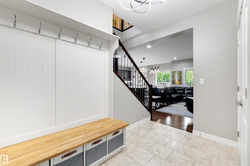 Entryway featuring a built-in bench with a light wood-finish top, white vertical paneling, and an upper shelf with metal hooks - 1507 Wates Place Sw, Edmonton, AB 