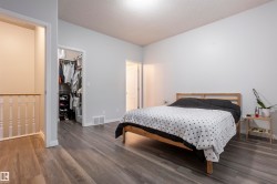 Bedroom featuring wood-finish flooring, a built-in closet, and a white spindle railing - 