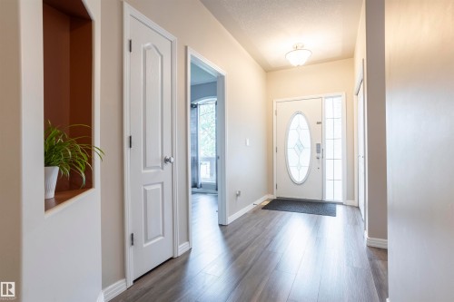 Foyer featuring wood-finish flooring, a white front door with oval frosted glass, and a frosted glass sidelight - 1441 Highwood Boulevard, Devon, AB 