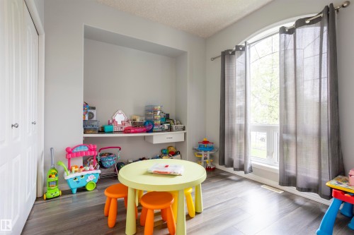 Room featuring wood-finish flooring, a built-in shelving unit, and a large arched window with transom detailing - 1441 Highwood Boulevard, Devon, AB 