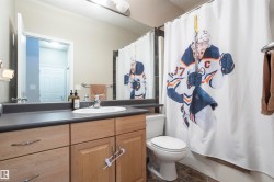 Bathroom featuring a single vanity with a white oval sink and chrome faucet, light wood-finish cabinetry, a dark countertop, and tiled flooring - 