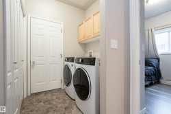 Dedicated laundry area featuring a tile-patterned floor, overhead cabinetry, and two bi-fold closet doors - 