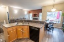 Kitchen island with a dual-basin stainless steel sink, a stainless steel faucet, wood-finish cabinetry, and a built-in dishwasher - 1441 Highwood Boulevard, Devon, AB 