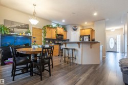 Open-concept kitchen and dining area featuring wood-finish flooring, recessed lighting, light wood cabinetry, and a kitchen island with a breakfast bar - 