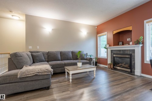 Living area featuring wood-finish flooring, a white trim fireplace with a dark tile surround, and two windows with blinds - 1441 Highwood Boulevard, Devon, AB 