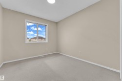 Neutral-toned room featuring a single window and light-colored carpet - 