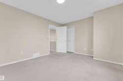 Spacious room featuring neutral carpeting, light beige wall paint, white trim, and a flush mount ceiling light - 