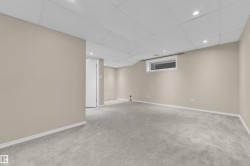Spacious room featuring neutral paint, gray carpeting, a drop ceiling with recessed lighting, white baseboards, and a high-set horizontal window - 