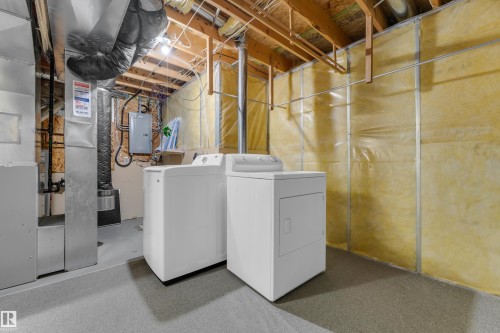 Dedicated utility area featuring a washer and dryer, exposed ceiling joists, and insulated walls - 3134 30 Avenue Nw, Edmonton, AB 