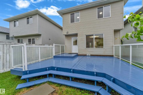Spacious rear deck featuring a vibrant blue finish, multi-level design, built-in benches, and modern glass panel railings - 3134 30 Avenue Nw, Edmonton, AB 