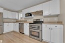 Kitchen featuring white shaker-style cabinetry, stainless steel appliances, light wood-finish flooring, a mosaic tile backsplash, and a double oven range - 3134 30 Avenue Nw, Edmonton, AB 