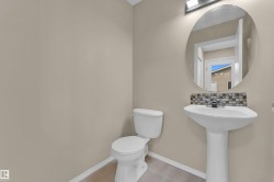 Bathroom featuring a pedestal sink, round wall mirror, mosaic tile backsplash, and light neutral wall finishes - 