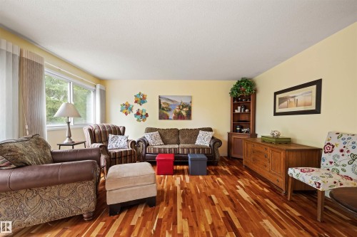 Living area featuring wood-finish flooring, light yellow walls, and a large window - 31 Royal Road, Edmonton, AB 