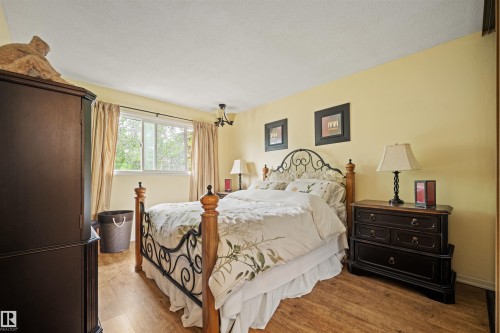 Bedroom featuring wood-finish flooring, a white-framed window, and a ceiling light fixture - 31 Royal Road, Edmonton, AB 