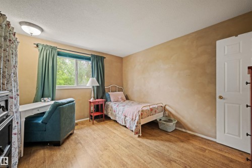 Wood-finish flooring throughout, featuring a window with natural light, a white interior door, and a flush-mount ceiling light fixture - 31 Royal Road, Edmonton, AB 