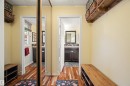 Entryway featuring wood-finish flooring, a full-length mirrored closet door, and a built-in wooden storage bench - 31 Royal Road, Edmonton, AB 