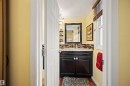 Bathroom featuring a dark wood vanity with a light-colored countertop, mosaic tile backsplash, framed mirror, and wood-finish flooring - 31 Royal Road, Edmonton, AB 