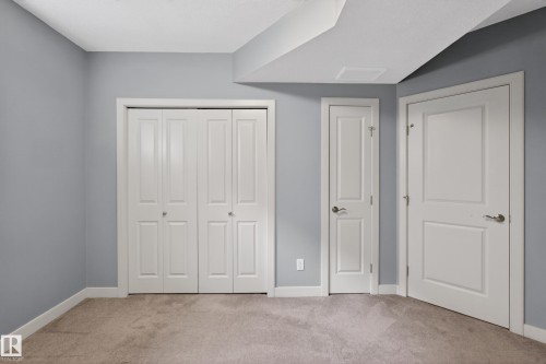 Blue painted walls featuring white trim, bi-fold closet doors, and two paneled doors with brushed nickel hardware - 624 Cantor Landing Landing, Edmonton, AB 