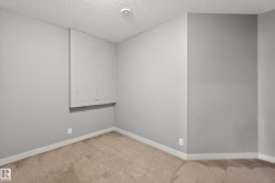 Interior space featuring light gray walls, white baseboards, and tan carpet flooring - 