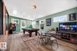 Entertainment room featuring wood-finish flooring, a vaulted ceiling, multiple windows, and a built-in media console - 