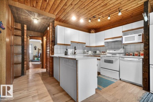 Kitchen featuring white cabinetry, white appliances, a white tile backsplash, and a wood-finish ceiling - 140 50047 Rge Rd 244, Rural Leduc County, AB 